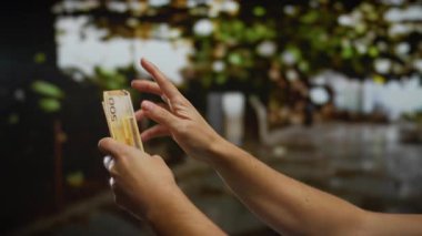 Norveçli kronu açık havada bulanık şehir zeminine karşı sayan bir adam, doğal ışıklandırması olan bir şehirde finansal işlemleri vurguluyor..