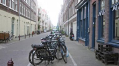 Amsterdam 'daki bulanık cadde, yerel mimariyi gösteren canlı bir şehir sahnesinde dar bir sokak boyunca uzanan çözünmüş bisikletlerle..