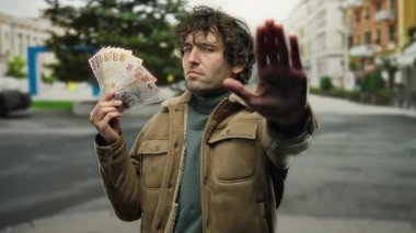 İspanyol adam elinde Türk lirası tutarak şehir sokaklarında bir duraklama hareketi yapıyor. Bu da açık havada mali bir karar verilmesini öneriyor..