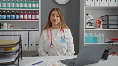 Üniformalı genç beyaz kadın doktor, kliniğe hoş geldiniz demek için sizi dostça bir jestle çağırıyor.