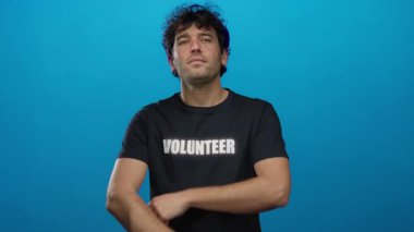 Gönüllü gömlekli İspanyol bir adam gülümsüyor ve kollarını mavi arkaplana karşı birleştiriyor, kendine güveni ve toplum ruhunu somutlaştırıyor..