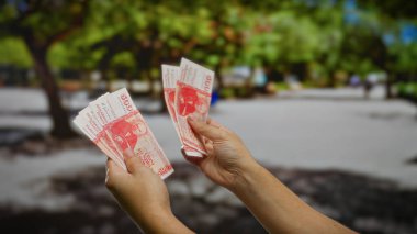 Açık şehir ortamında İzlanda Krona banknotları tutan eller, bir şehir parkındaki mali planlama veya yatırım faaliyetlerini akla getiriyor.