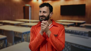 Turuncu tulumlu bir adam, masaların arka planında bulanık bir şekilde el çırpıyor. Alışılmadık bir hapishane atmosferi yaratıyor. Umut ve değişime odaklanıyor..