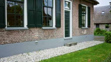 Yeşil kepenkleri ve yemyeşil çimenleri olan büyüleyici tuğladan bir evin bulanık manzarası. Huzurlu bir mahalle ortamında klasik mimari ve sakin bir ortam sergiliyor..