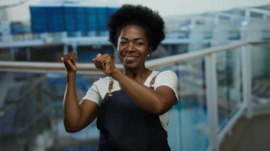 Açık havada önlük giymiş, denizde gülümseyen bir kadın rahat bir denizcilik ortamında eğlence ve heyecan sergiliyor..