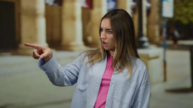 Şehir ortamında düşünceli bir ifade takınan, sarı saçlı, rahat giyinen, doğal ışık saçan, modern bir şehir havası sergileyen bir kadın..