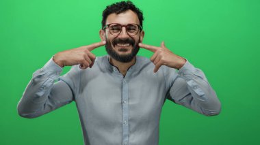 Sakallı, gülümseyen ve yeşil arka planda kendini gösteren İspanyol bir adam güven ve mutluluk taşıyor..