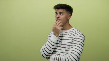 Sarı arka plan üzerinde düşünceli bir genç, çizgili bir gömlek giyiyor, içsel ve ilginç bir tavır sergiliyor..