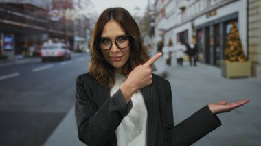 Gözlüklü genç İspanyol kadın kenar mahallede kendine güvenen bir şekilde poz verirken kenarı gösteriyor..