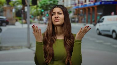 Kalabalık bir şehir caddesinde kafası karışmış bir kadın. Yoğun trafik ve bulanık bir geçmişi var. Kaldırılmış eller ve uzun dalgalı saçlarla kafa karışıklığı yaşıyor..