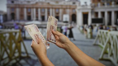 Vatikan 'da St. Peter Bazilikası önünde el ele tutuşan eller, kentsel bir ortamda yatırım ve seyahat kavramlarını resmediyor.