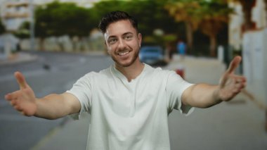 Sakallı genç adam şehir sokaklarında gülümsüyor, neşe ve kollarını şehir ortamında açıyor..