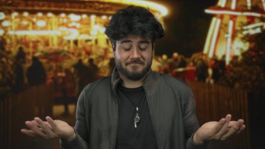 Geceleri açık havada sakallı genç bir adam aydınlık arabalarla çevrili dalgın dalgın dalgın bakıyor neşeli ama içsel bir atmosfer yaratıyor..