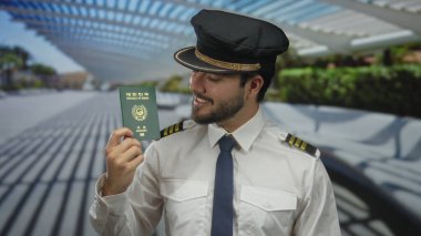 Hava yolları üniforması ve şapkası giyen bir adam güneşli bir sokakta Güney Kore pasaportunu elinde tutuyor. Gözleri kapalı gülümsüyor, modern mimari ve canlı yeşilliklerle çevrili..