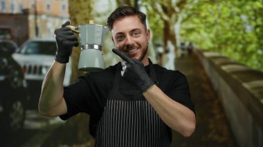 Önlüklü genç adam, elinde kahve makinesiyle şehir caddesinde sakallı garson, arka planda ağaçlar ve arabalarla bira ekipmanları sunuyor..