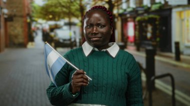 Şehir caddesinde kendine güveni tam bir Salvador bayrağı taşıyan kadın, farklı kimlikler ve açık hava ortamında uluslararası kültür karışımı sergiliyor..