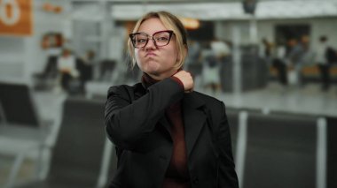 Kadın jestleri havaalanı terminalinde gözlük takıyor sarışın beyaz kadın ciddi ifade seyahat konsepti arka plan meşgul çevre görüntüleme anı