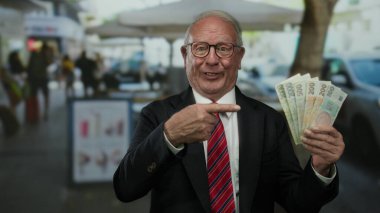 Czech Koruna banknotlarını elinde tutan kıdemli bir adam hareketli bir açık hava restoranının terasında iş ortamında neşe ifade ediyor..