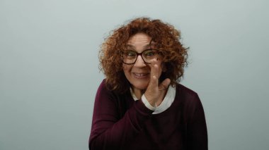 Dışlanmış beyaz bir arka plana karşı duran anlamlı bir yüzle bir sırrı fısıldayan bir kadın..