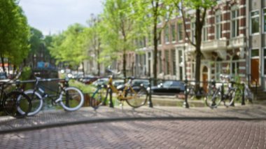 Amsterdam 'da bir kanalın yakınındaki bisiklet manzarası bulanık. Arka plan yerinden çıkmış klasik mimari ve gür ağaçları gösteriyor..