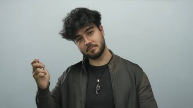 Sakallı genç İspanyol bir adam kamerayı beyaz bir arkaplana doğrulturken bir kronometre tutuyor ve aciliyet ve zaman yönetimi hissi veriyor..