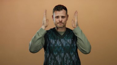 Genç İspanyol bir adam, elleri ile bir çerçeve hareketi yapıyor izole bir kahverengi duvar arkaplan yaratıcı ifade ileten
