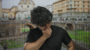 Güneşli bir günde, Roma harabelerinde sakallı genç bir adam tarihi mimariye karşı dalgın bakıyor..