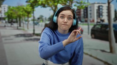 Kulaklıklı esmer kadın, sokakta öfkeyle jestler yapıyor, şehirsel duyguları ve dinamik etkileşimleri vurguluyor..