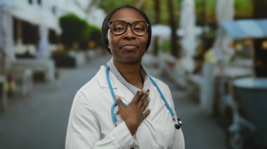 Beyaz önlüklü ve steteskoplu kadın doktor şehir arka planında profesyonel sağlık hizmeti sunan şehir sokaklarında öpüştü..