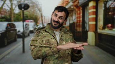 Ordu üniformalı İspanyol bir adam. Yoğun bir sokakta sakallı jestler yapıyor. Para kavramını anlatıyor..