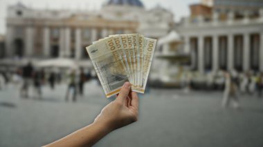 Vatikan 'ın St. Peter Meydanı' ndaki açık havada Danimarka kronu 'nun el ele tutuşması turistlerle dolu dini bir ortamda kültürel zıtlığı vurguluyor..