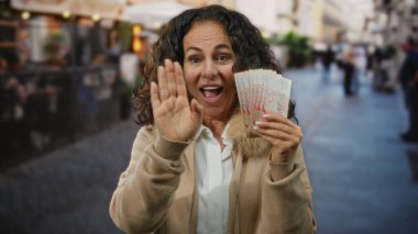 Kalabalık bir caddede elinde Singapur dolarlarıyla gülümseyen ve kameraya el sallayan bir kadın..