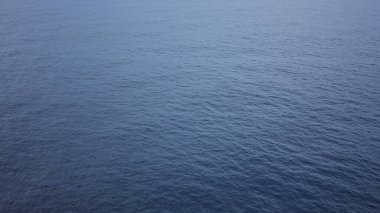 Sakin okyanus manzarası, berrak gökyüzünün altında, arka planlar için mükemmel, izole ve doğal bir ortamda dinginlik ve sükunet uyandıran sonsuz mavi suyu gösteriyor.