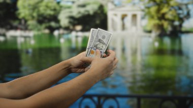 Amerikan dolarlarını açık hava parkında tutan adam, doğal bir bahçe ortamında finans ve ekonomiyi ön plana çıkarıyor..