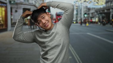 Şehrin arka planında neşeli bir poz veren genç adam geçen araçlar ve mimari detaylarla dolu hareketli ve dinamik bir atmosfer izlenimi veriyor..