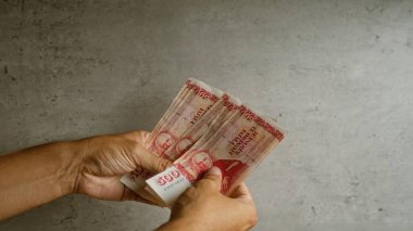 Elleri somut bir zemine karşı İzlanda Krona banknotları tutuyor