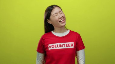 Kırmızı gönüllü gömlekli kadın neşeli sarı bir arka planda neşeli ve toplum temalı ifadeleri canlandırarak neşeli bir şekilde gülümsüyor..