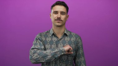 İzole edilmiş mor arka plan önünde yumruğuyla el kol hareketi yapan, kararlılık ve odaklanma gösteren, kendinden emin ve iddialı bir tavrı vurgulayan genç adam..