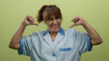 İspanyol kıdemli kadın kendini çizgili bir temizlik üniformasıyla izole edilmiş sarı bir arka plana göstererek temizlikçi olarak rolünü vurguladı..