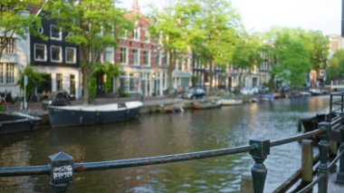 Tekneler ve klasik binalarla dolu bulanık şehir manzarası, çözünmüş yeşil ağaçlar ve güneşli bir günde pitoresk şehir manzarası.