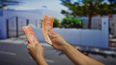 Şehirdeki bir sokakta Filipinli pesoları tutan adam, şehir merkezinde elinde banknotlarla iş yatırımını sembolize ediyor..