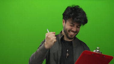 Sakallı genç adam kırmızı panoyu tutarken canlı yeşil arka plana karşı hislerini ve ifadesini İspanyol erkeklerinde gösteriyor.