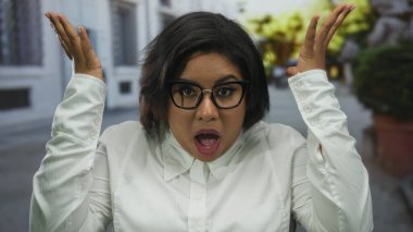 Gün boyunca açık şehir ortamında ellerini kaldırarak şaşkınlığını ifade eden bir kadın sokakta şaşkınlık içinde..