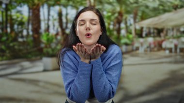 Esmer bir kadını öpen Terrace Caddesi Restoranı gülümsüyor. Öpücük gönderiyor. Arka plan mavisi.