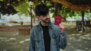 Fransız pasaportlu bir adam, yeşil ağaçlarla çevrili sakin şehir ortamının ortasında güvenli bir şekilde gülümsüyor, patikada yumuşak gölgeler bırakıyor..