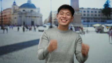 Vatikan 'da gülümseyen genç bir adam arka planı olarak güzel bir tarihi kare ile, canlı bir şehir atmosferini yakalıyor..