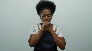 Kadın elini göğsüne koyup öksürüyor. Beyaz arka planda izole edilmiş. Sağlık bağlamında önlük giyiyor.