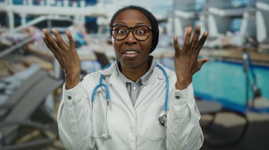 Lüks bir deniz havuzu alanında dışarıda duran kadın doktor. Stetoskop ve açık gökyüzü arka planına sahip güneşli limanda odaklanmış beyaz önlükle kafası karışmış görünüyor.