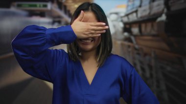 Gülümseyen ve neşe içinde gözlerini kapayan bir kadın, bir yolcu güvertesinde rahatlatıcı bir anın keyfini çıkarırken, canlı mavi bir bluz giyerek, denizcilik arka planına yaslanmış..