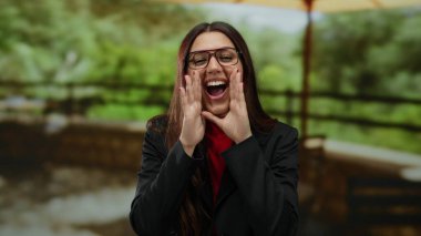 Genç İspanyol kadın yemyeşil bir açık hava parkında neşeyle bağırıyor, canlı enerji ve heyecanı vurguluyor..